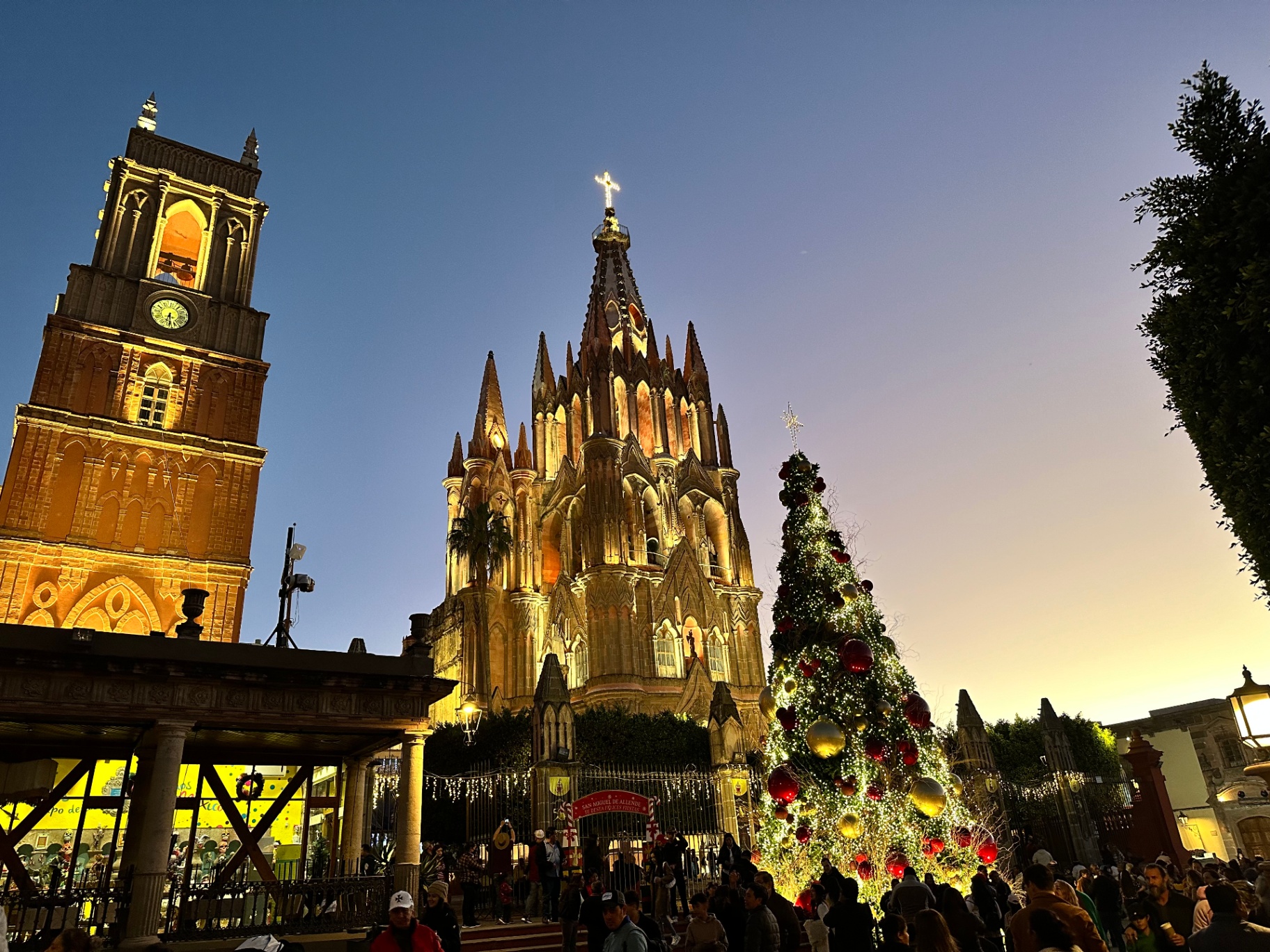 Parroquia de San Miguel Arcángel iluminada al anochecer con árbol de Navidad